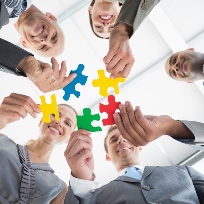 Business colleagues holding piece of puzzle in the office