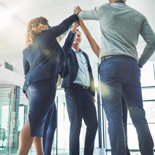 Shot of a group of coworkers high fiving together in an office